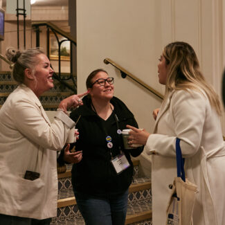 three women chatting outside a conference room